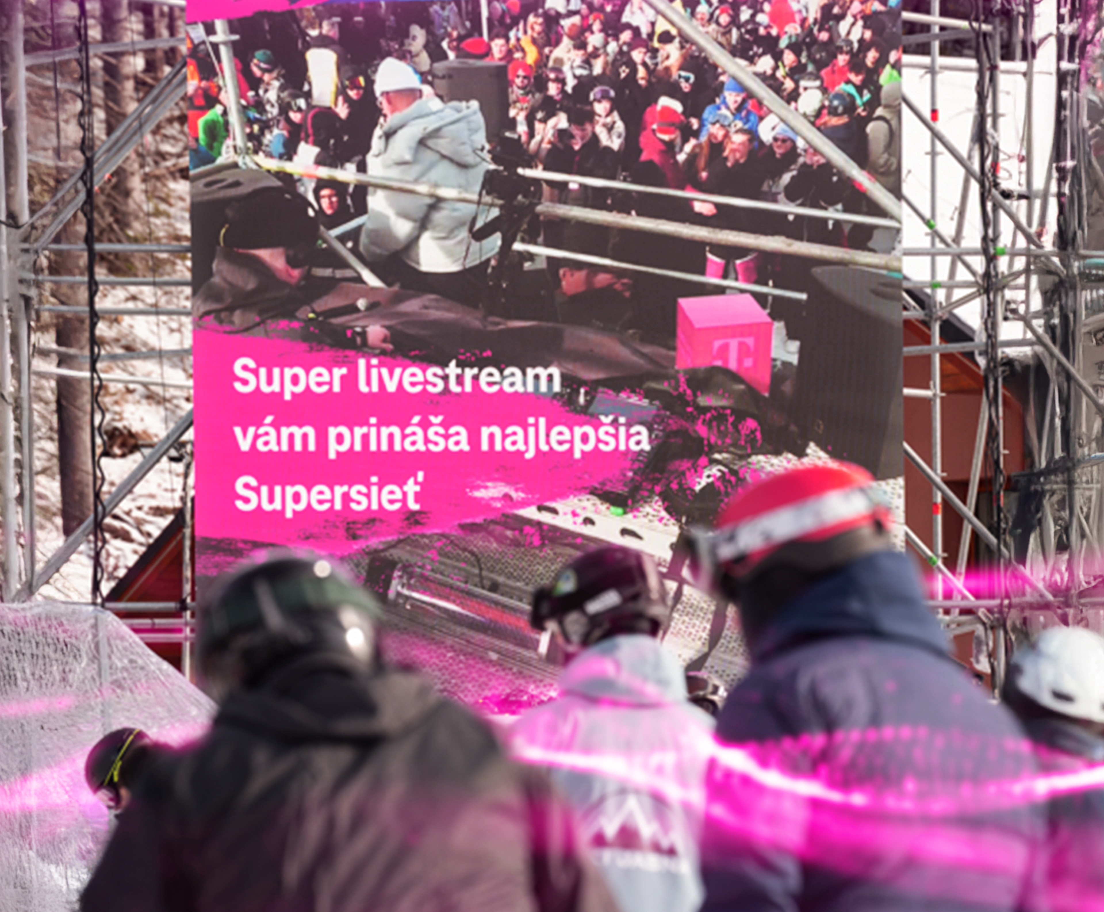 Lyžiari sledujú video stenu s reklamou na livestreame v slovenských horách.