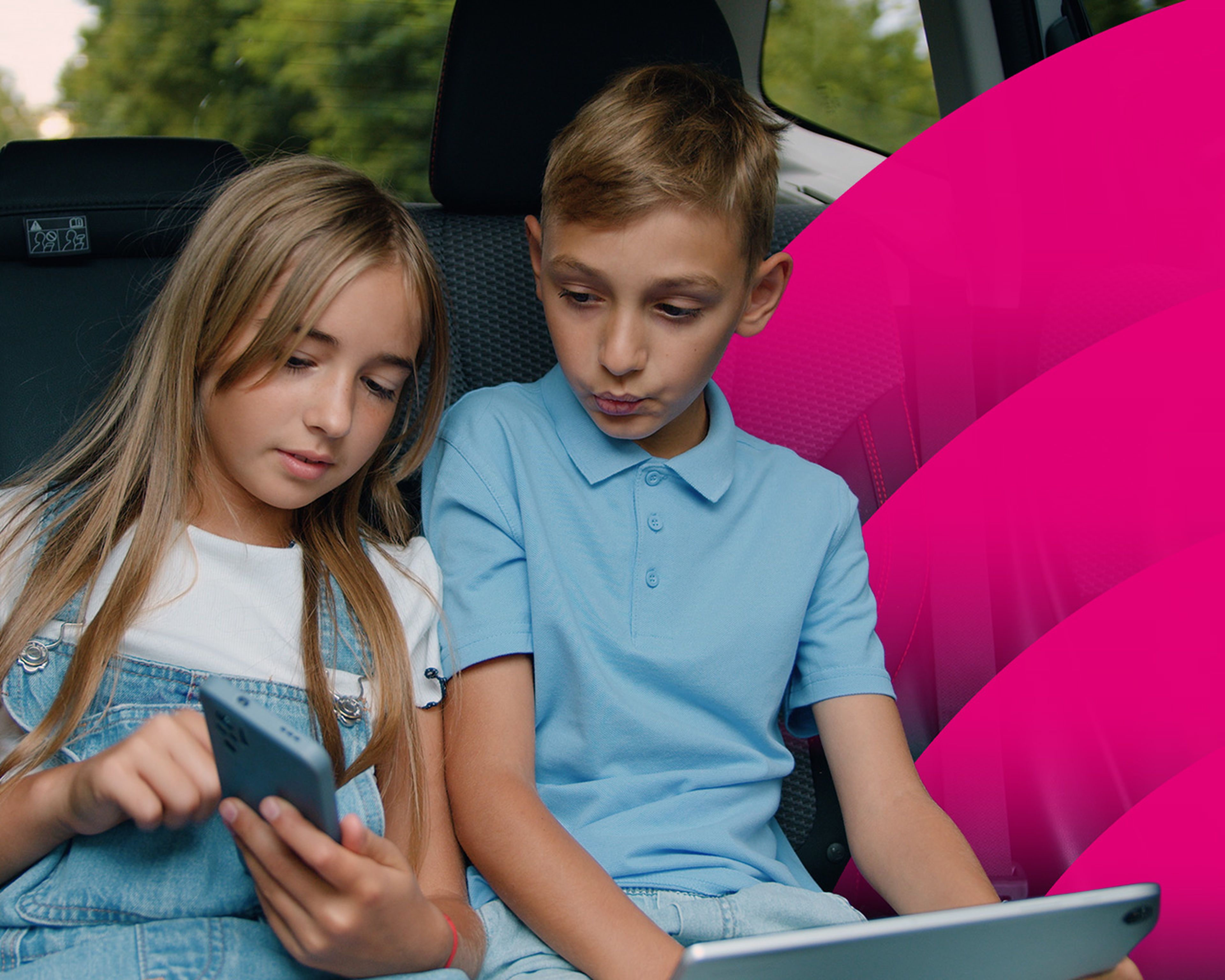 Dve deti na zadnom sedadle auta, jedno so smartfónom a druhé s tabletom, sústredené na svoje obrazovky. Vpravo je jasne ružová grafika.