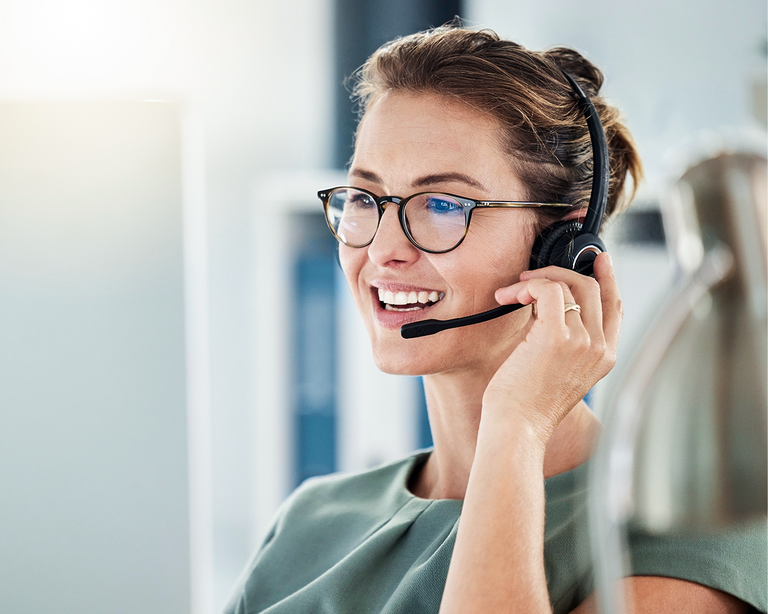 Žena s headsetom usmievajúca sa pri telefonovaní v kancelárii.