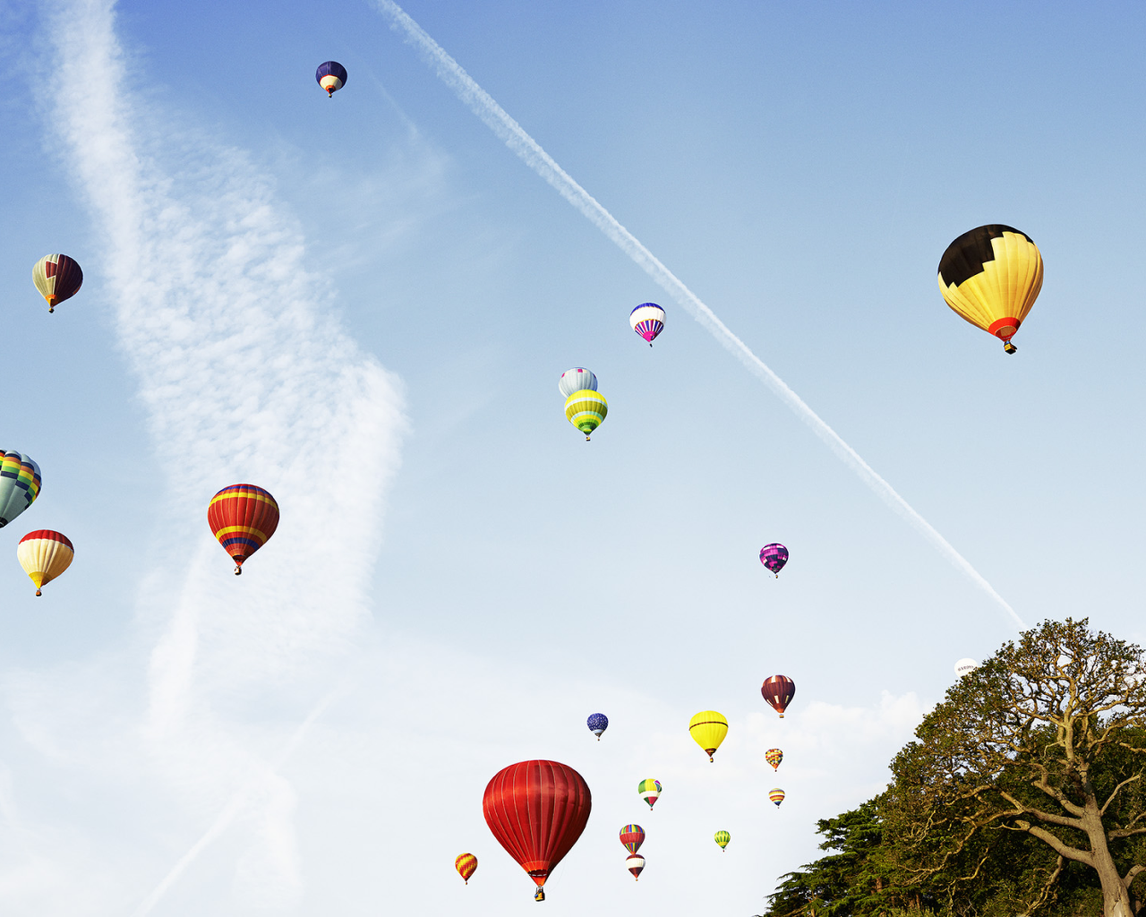 Horkovzdušné balóny rôznych farieb stúpajú na oblohe počas jasného dňa.