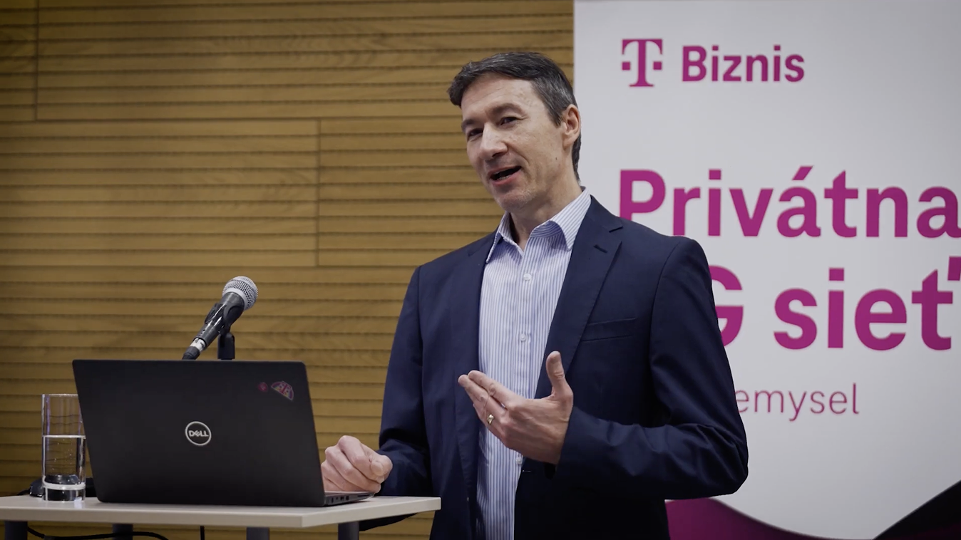 Video predstavuje ukážku biznis riešení Telekom pre digitalizáciu výroby: privátna 5G sieť, rečník pri stole s prezentačným vybavením, za ním banner s logom Telekom Biznis a textom o 5G technológii.