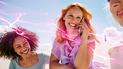 Usmievajúca sa žena telefonuje vonku, obklopená ružovými svetelnými efektmi telekom