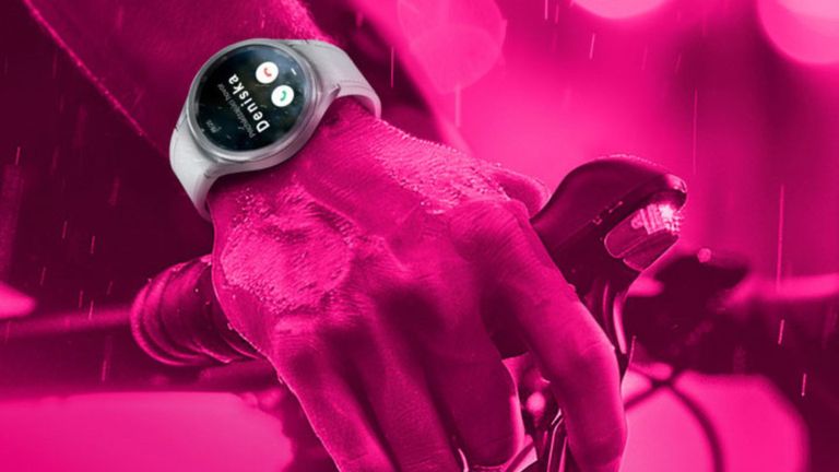 Detailný záber ruky zvierajúcej riadidlá bicykla s inteligentnými hodinkami zobrazujúcimi fitness aplikáciu. Obrázok má ružový odtieň s kvapkami vody.