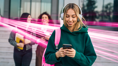 Žena so slúchadlami a mobilom, okolo nej ružové svetelné pruhy.