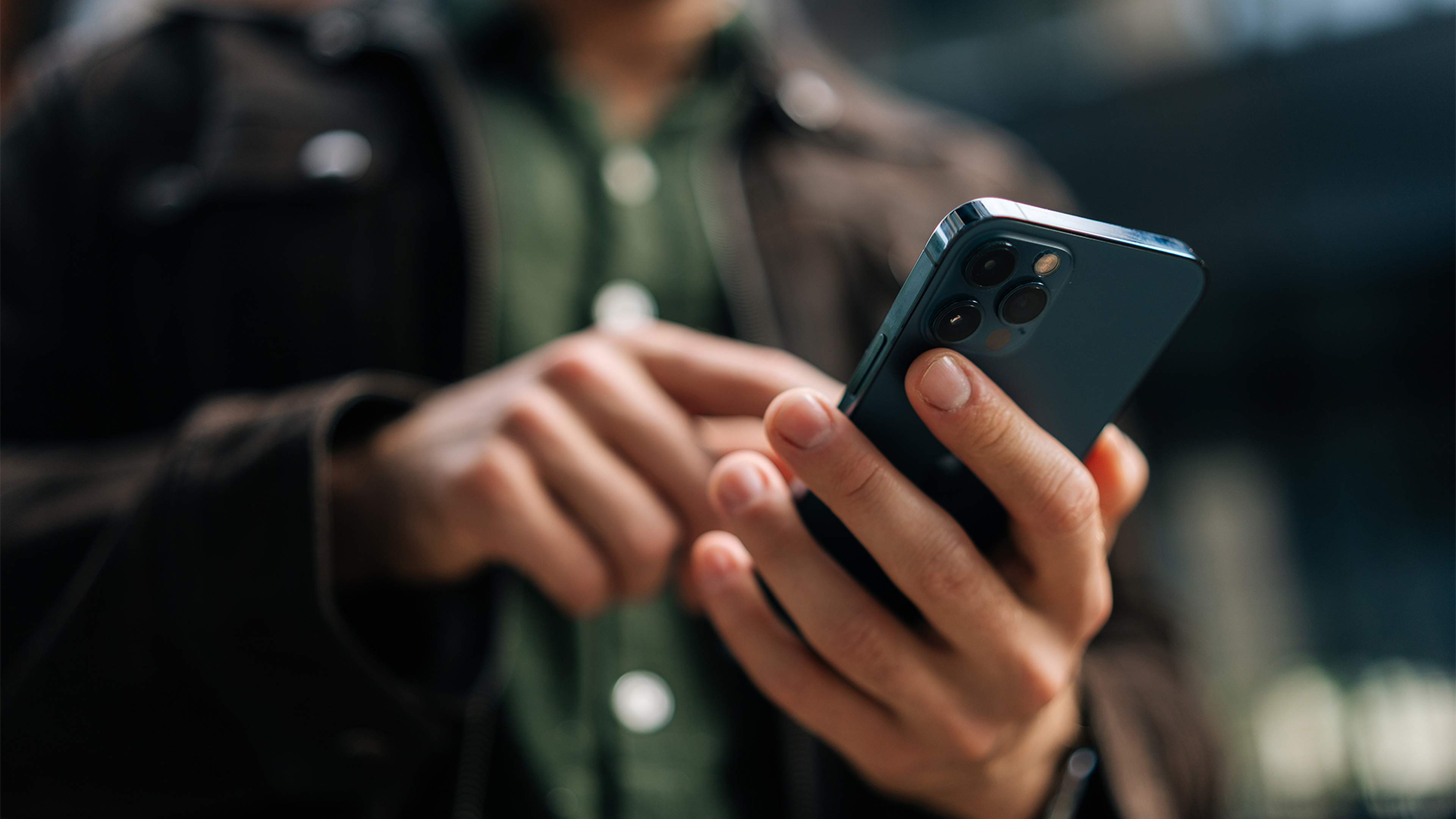 Osoba drží mobilný telefón a používa ho.