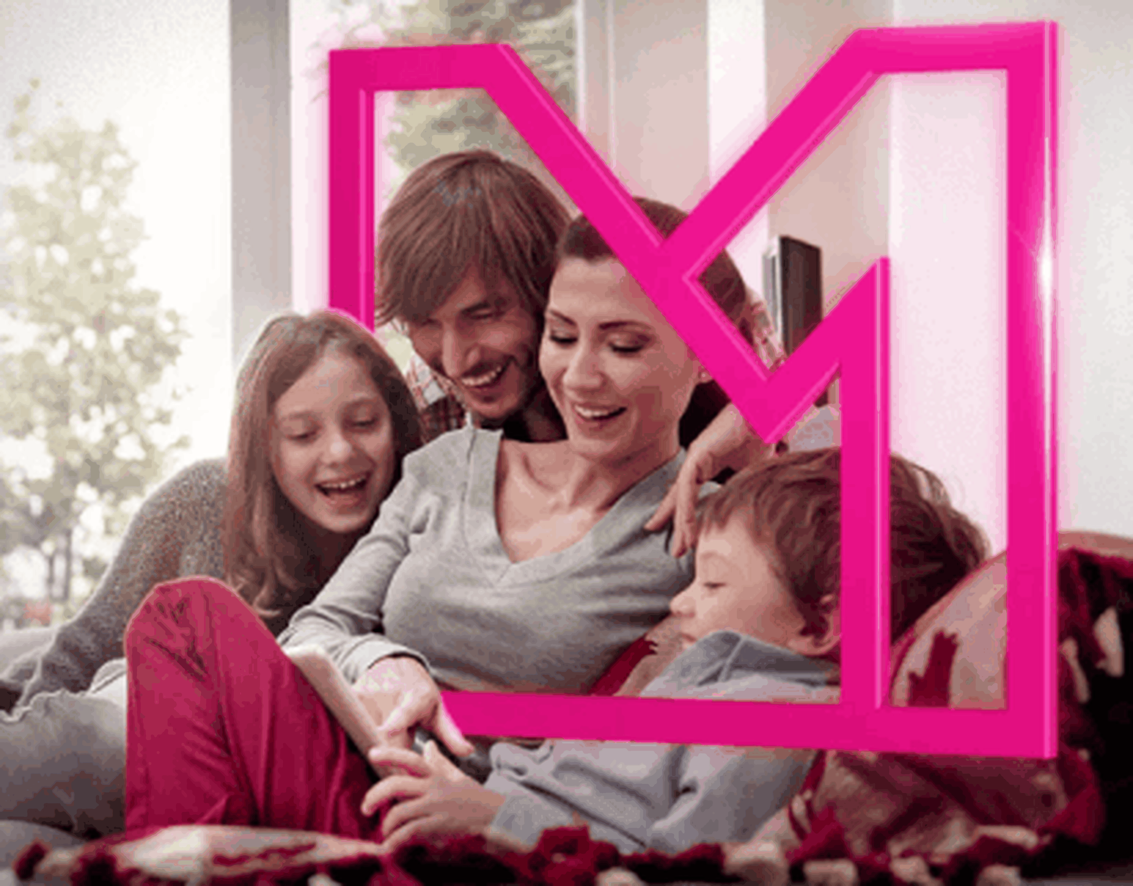 Usmievavá štvorčlenná rodina vrátane dvoch detí relaxuje spolu v interiéri s veľkým ružovým rámom s písmenom „M“ v popredí.