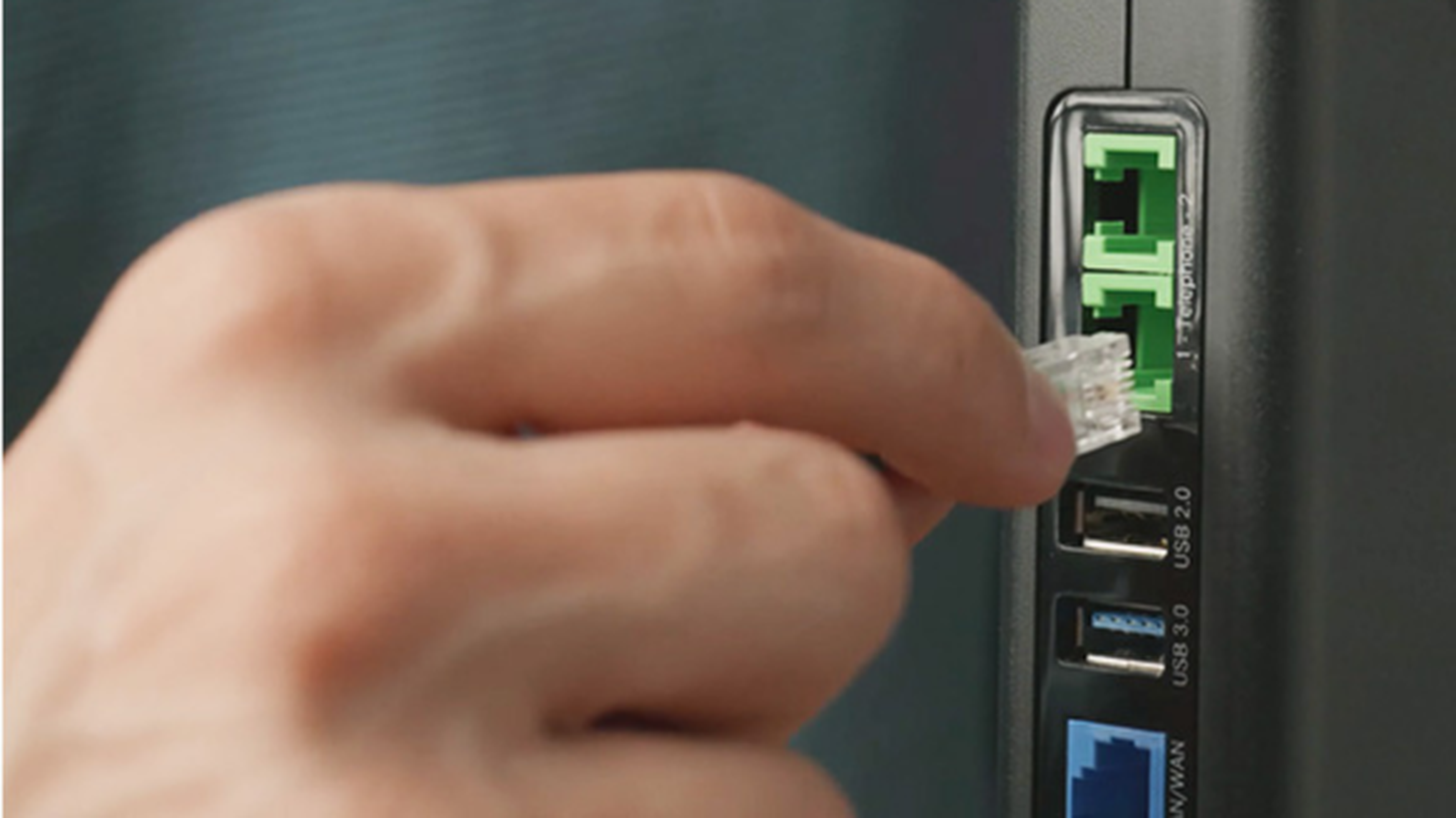 Ručné zapojenie ethernetového kábla do routera s viditeľnými USB portami a sieťovými pripojeniami.