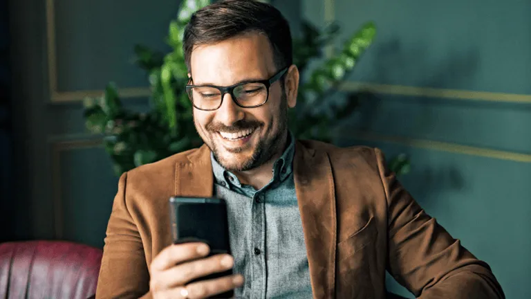 Muž s okuliarmi prezerá mobil v kancelárii – vizuál služby InLine Security od Telekomu.