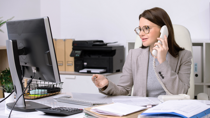 Administratívna pracovníčka telefonuje v kancelárii - znázorňuje stabilnú sieť pre úradné procesy.