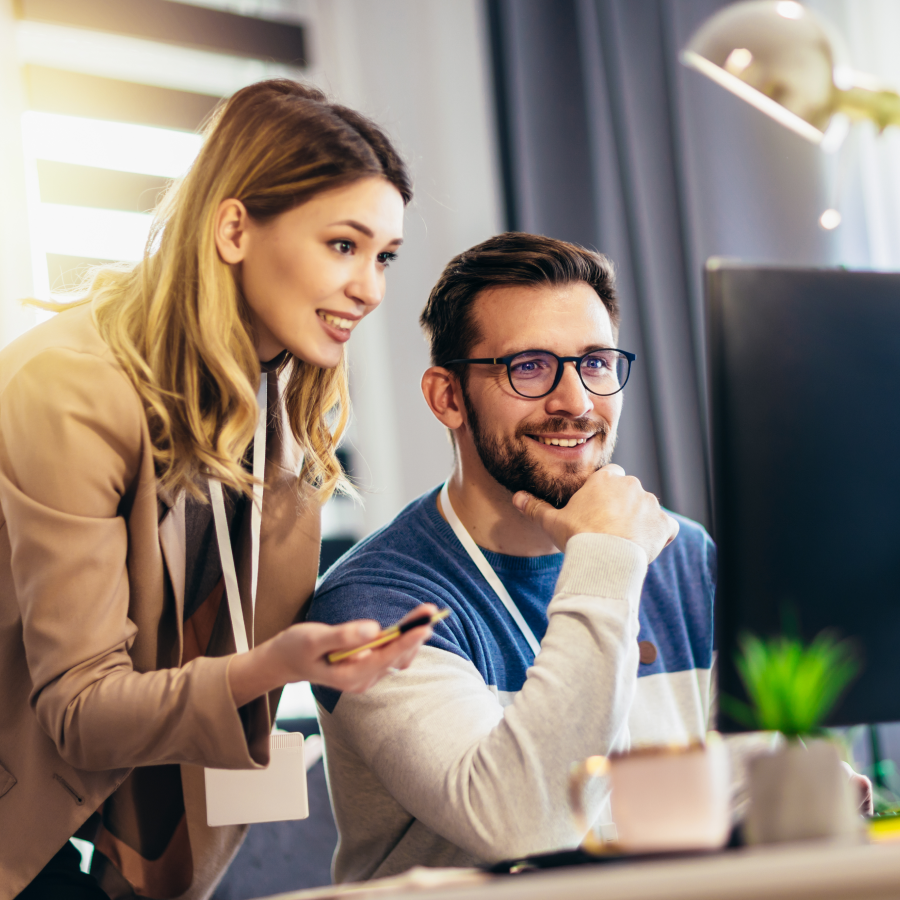 Kolegyňa a kolega spoločne pracujú pri monitore v kancelárii – vizuál služby Microsoft 365 pre firmy od Telekomu.