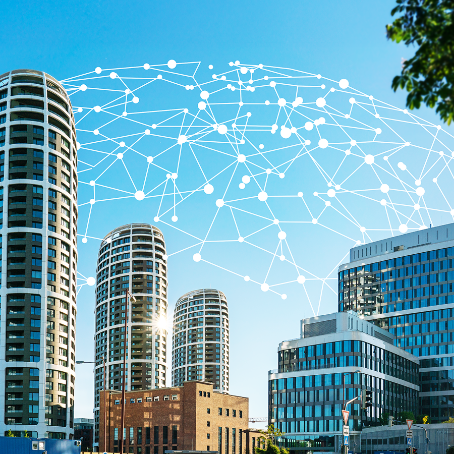 Moderné kancelárske budovy s digitálnou vizualizáciou siete nad nimi. Symbolizujú prepojenie IoT zariadení a zber dát v reálnom čase pre efektívnejšie podnikanie.